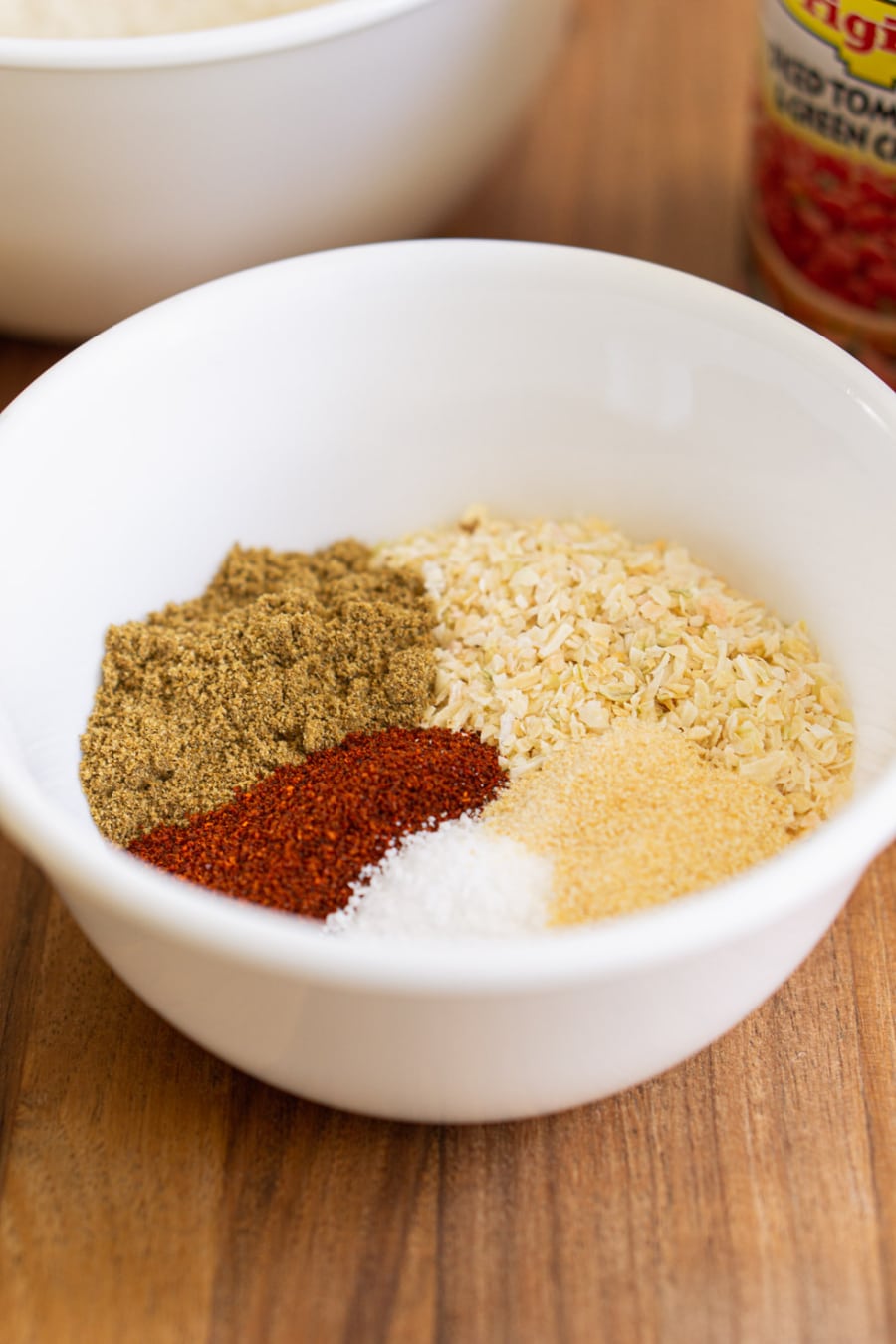 a bowl of spices for making ground beef and rice including dry minced onions, cumin, chili powder, garlic powder, and salt