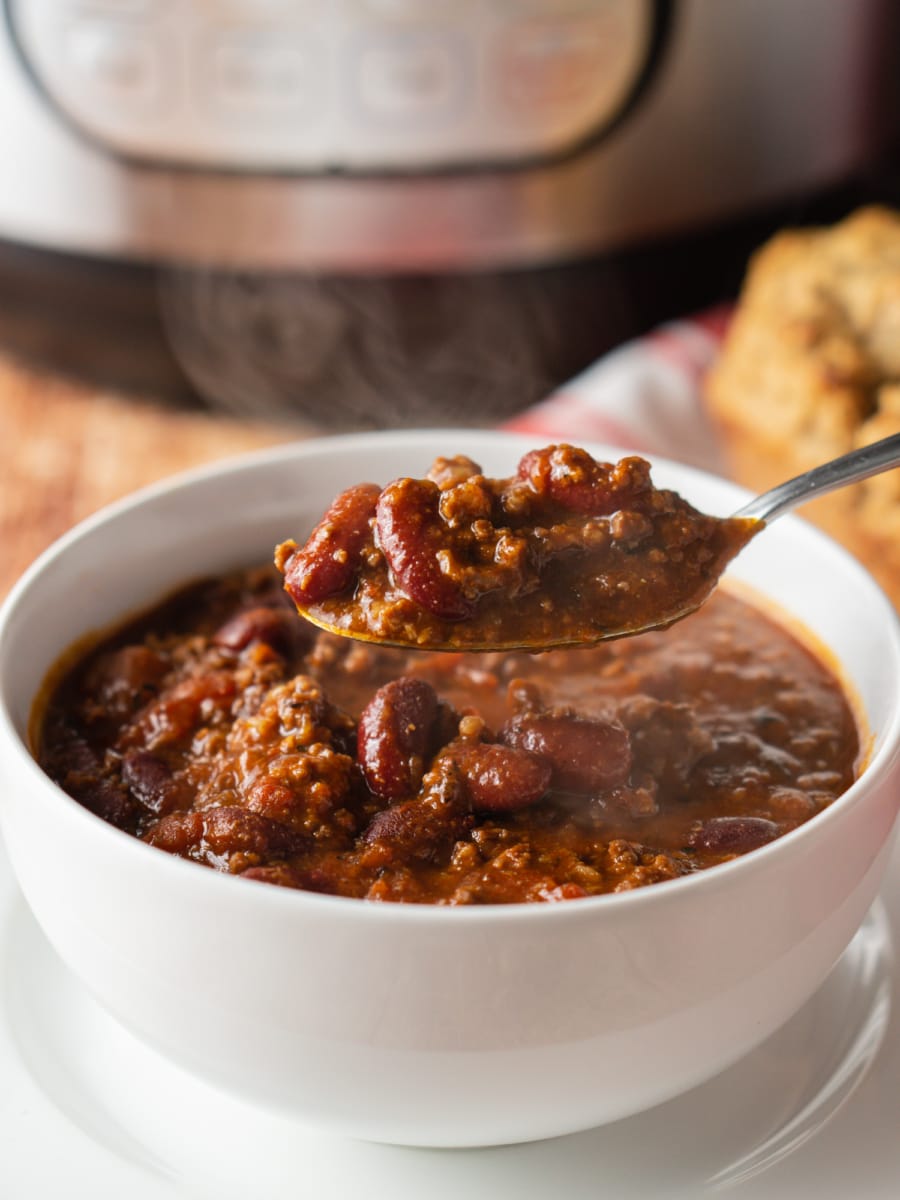  a spoonful of chili being scooped out of a bowl