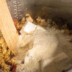 adding cream cheese and parmesan to tuscan chicken pasta in the instant pot