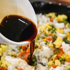 adding soy sauce to a skillet to make easy vegetable and egg fried rice