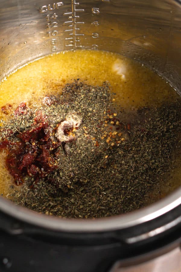 adding spices to the instant pot for tuscan chicken pasta
