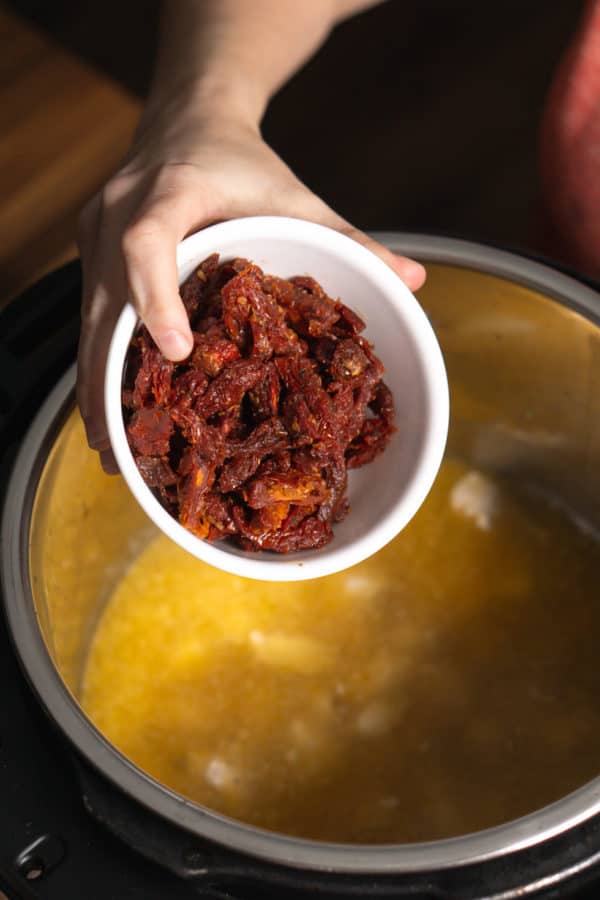 adding sun-dried tomatoes to the instant pot for tuscan chicken pasta