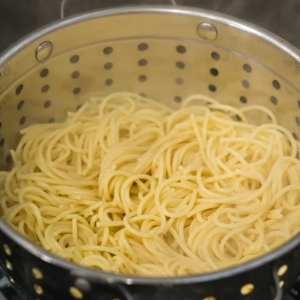 draining spaghetti to make spicy spaghetti aglio e olio