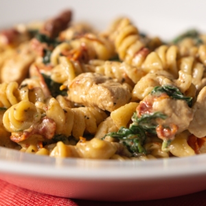 a close up of tuscan chicken pasta served on a plate