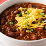 chili in a bowl topped with shredded cheese and green onions