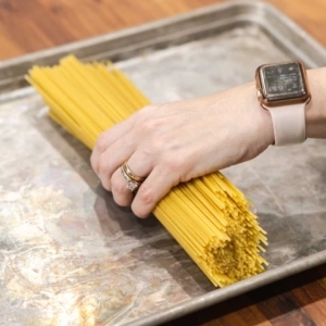 laying out spaghetti pasta on a baking sheet