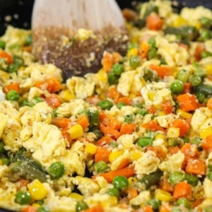 a skillet full of scrambled egg and mixed vegetables for making homemade chinese egg fried rice