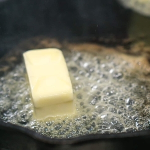 melting a stick of butter in a cast iron skillet