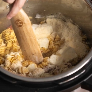 mixing cream cheese and parmesan cheese into pasta in the instant pot to make tuscan chicken pasta