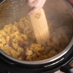 mixing cream cheese and parmesan cheese into pasta in the instant pot to make tuscan chicken pasta