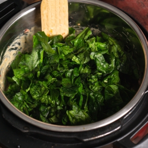 adding spinach to the instant pot to make tuscan chicken pasta