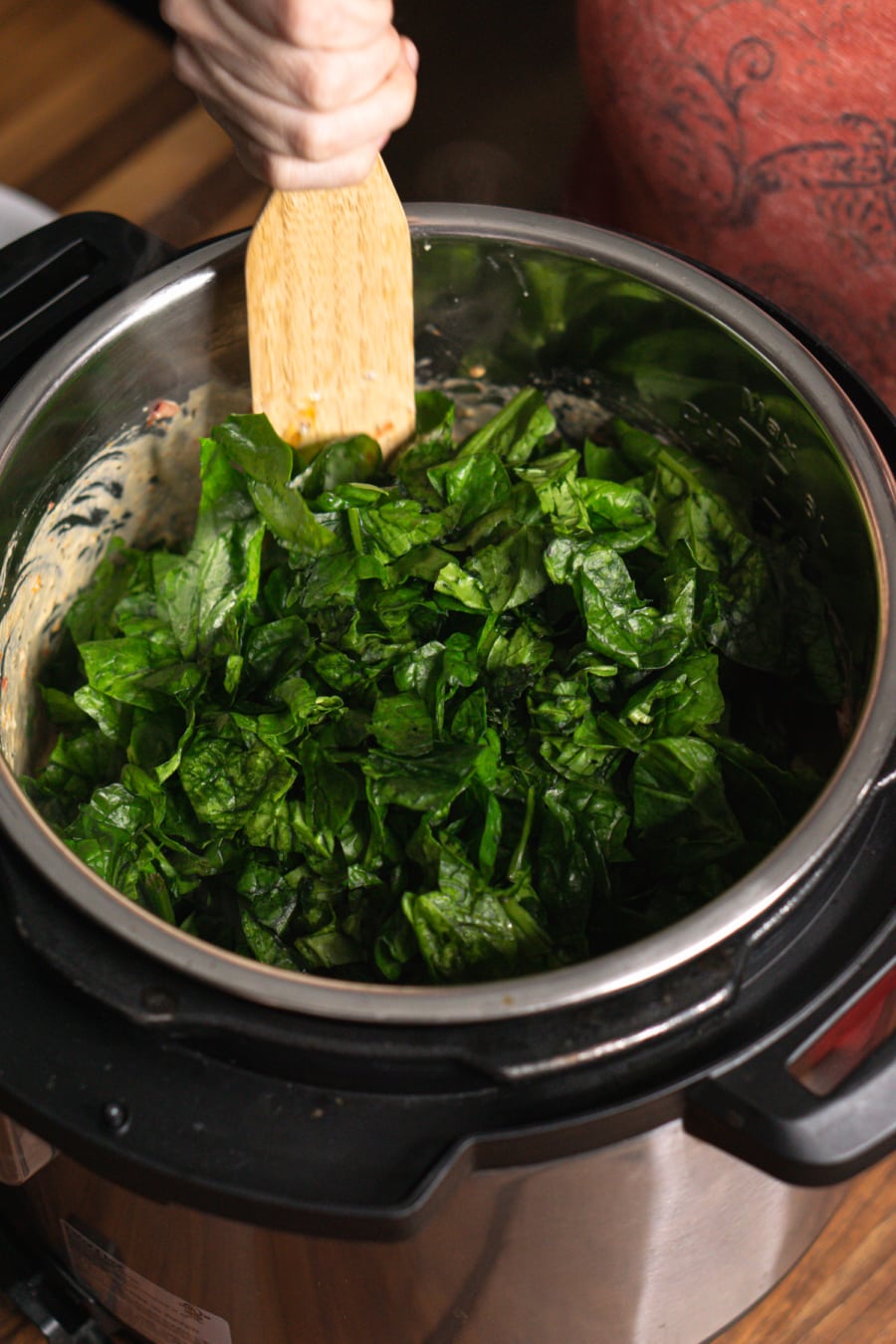 adding spinach to the instant pot to make tuscan chicken pasta