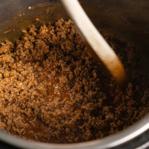 scraping down bottom of instant pot liner to remove pieces of stuck on ground beef and spices