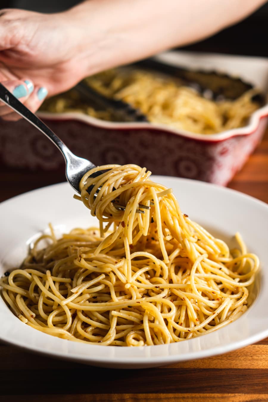 a plate of spicy olive oil spaghetti and a fork with the pasta wrapped around it