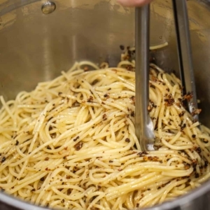 tossing spaghetti with olive oil in a large pot