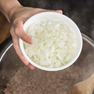 adding a small bowl of diced onion to a mixture of cooked ground pork and lean ground beef in the instant pot pressure cooker