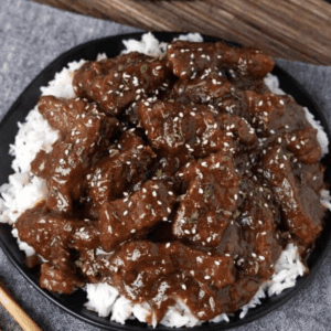 a plate of mongolian beef served over rice