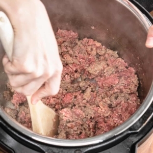 mixing and breaking apart a mixture of ground pork sausage and lean ground beef while they cook in the instant pot pressure cooker