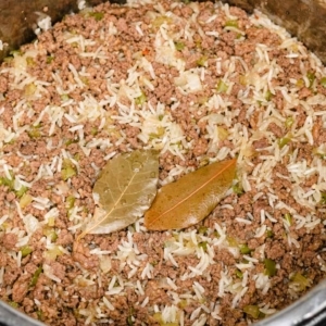 two bay leaves sitting on top of dirty rice after cooking in the instant pot pressure cooker