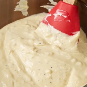 a creamy sauce in a mixing bowl with a spatula