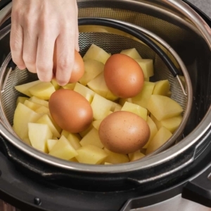 placing whole eggs on top of chopped potatoes in a wire mesh basket inside the instant pot