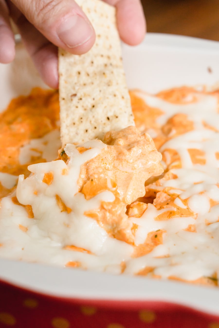 dipping a tortilla chip into a casserole of buffalo ranch chicken dip