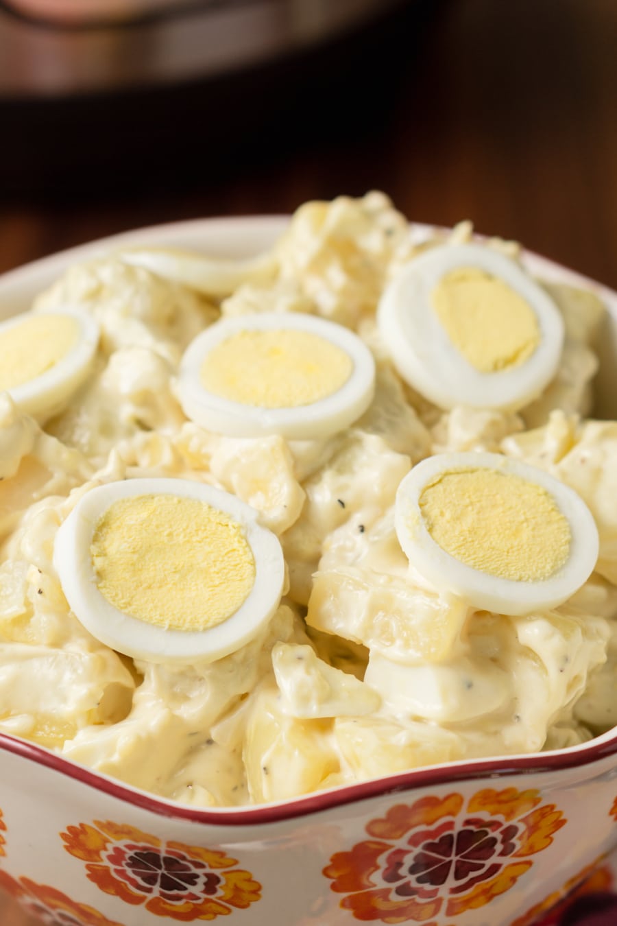 a bowl filled to the top with homemade potato salad and topped with slices of egg