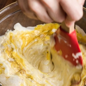 using a spatula to mix a creamy sauce in a large mixing bowl