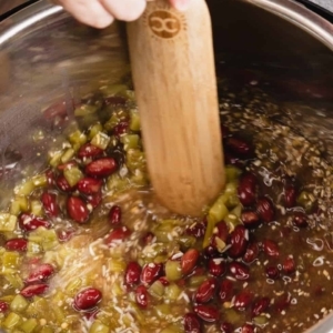 mixing rice, red kidney beans, diced green chiles, spices, and chicken stock in the instant pot using a spurtle