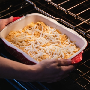 placing a casserole of buffalo ranch chicken dip in the oven