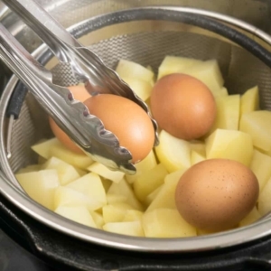 using a pair of tongs to remove hard boiled eggs from the instant pot