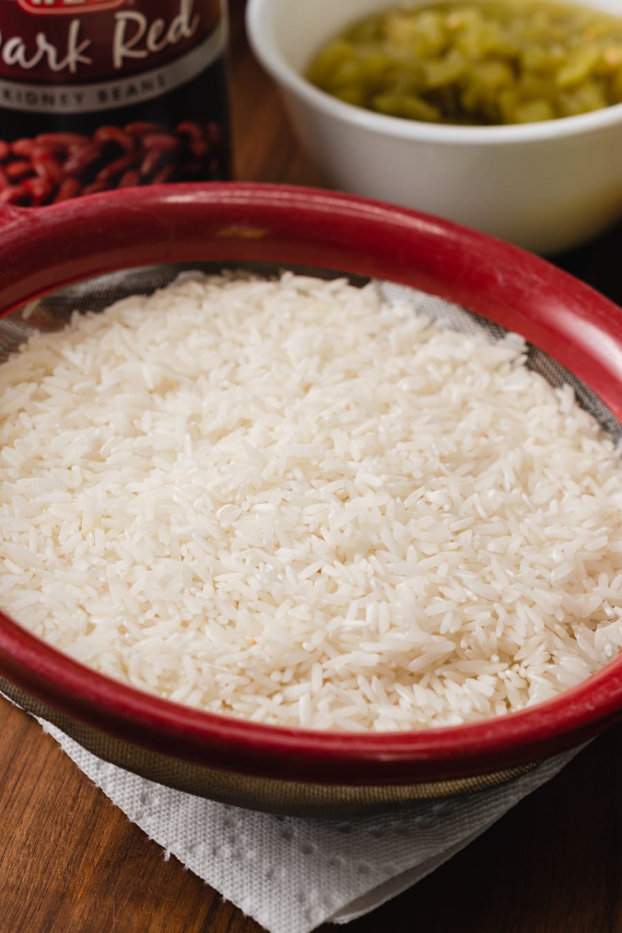 a fine mesh strainer filled with rinsed long grain white rice sitting on the counter drying