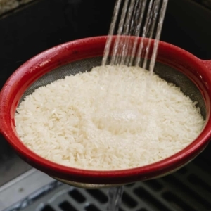 rinsing white long grain rice in a fine mesh strainer over the sink