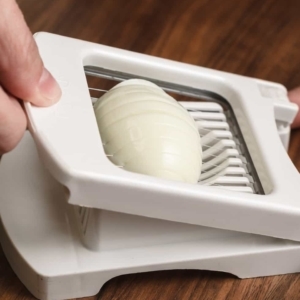 slicing a hard boiled egg using an egg slicer