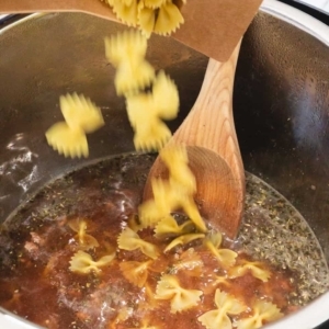 adding farfalle pasta to ground beef and beef broth in the instant pot