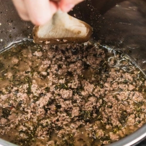 deglazing the instant pot with a wooden spoon after cooking ground