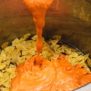 layering vodka sauce over farfalle pasta in the instant pot