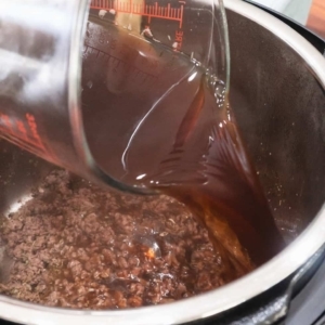 pouring three cups of beef stock into the instant pot