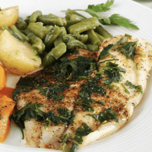 a plate of tilapia with green beans, carrots, and squash