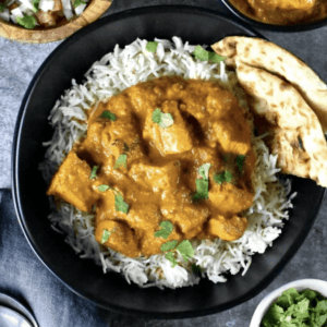 a plate of chicken tikka masala over a bed of rice