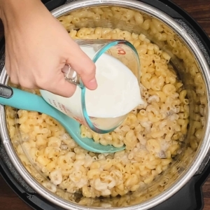 pouring milk into macaroni and cheese with mushroom soup in the instant pot