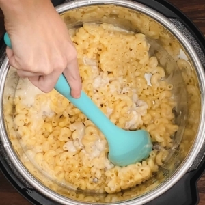 mixing cooked elbow pasta and cream of mushroom soup with a large silicone spoon in the instant pot