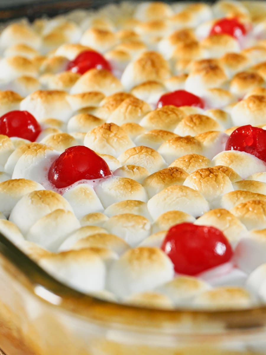 closeup of sweet potato casserole topped with marshmallows and cherries