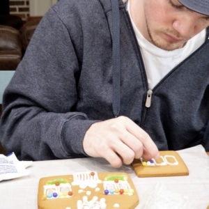 a adolescent boy decorating a gingerbread house