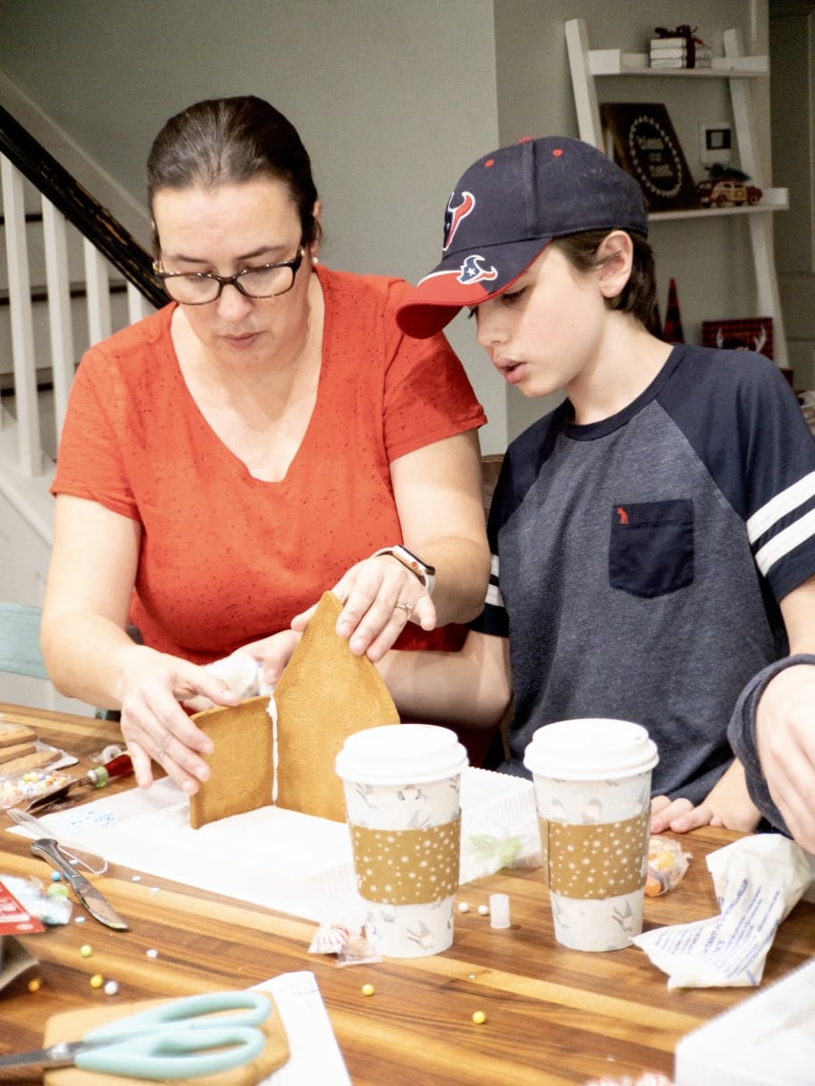 a mother and child building a gingerbread house together