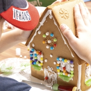 a young child building a gingerbread house