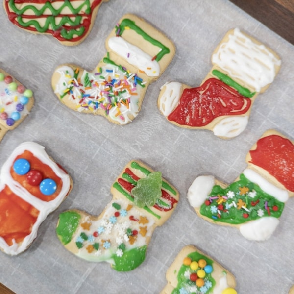 gingerbread stockings decorated with colorful icing siting on parchment paper