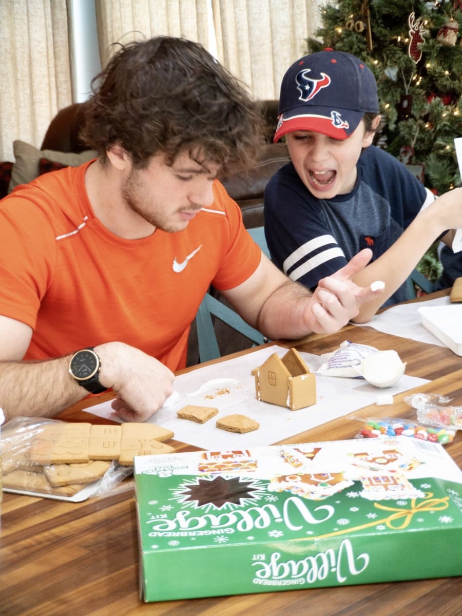 an older and younger brother building gingerbread houses together