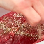 sprinkling salt, pepper, and garlic powder over a chuck roast in a slow cooker