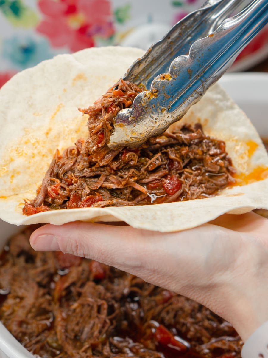 making a taco with crockpot carne mechada